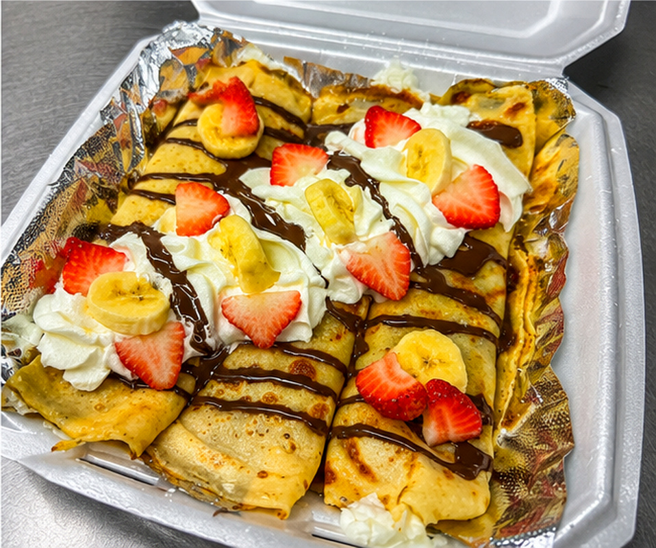Sweet crepes with strawberries, banana, Nutella drizzle, and whipped cream