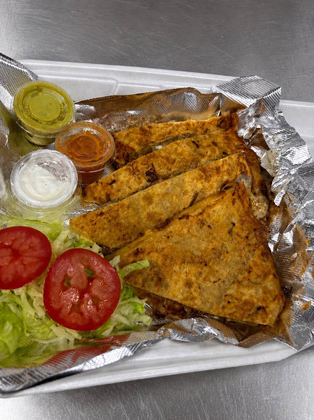 Quesadilla with meat, lettuce, tomato, crema, and salsa